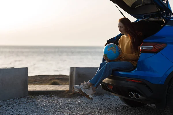 Милая случайная женщина готова к путешествию с глобусом в машине — стоковое фото