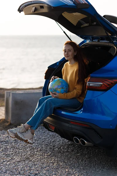 Cute casual woman ready for travel with globe in car — Stock Photo, Image