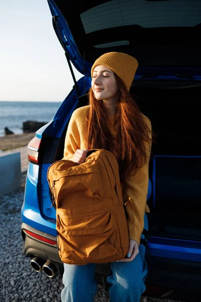 Kızıl saçlı, hoş, sıradan bir kadın arabayla yolculuğa hazır. — Stok fotoğraf