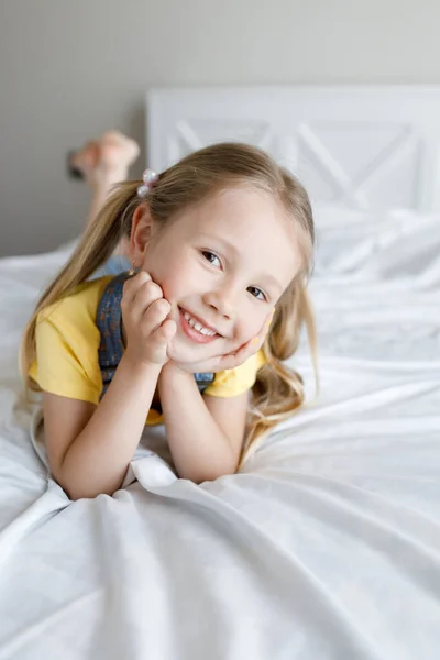 Linda niña en casa en la cama sonriendo — Foto de Stock