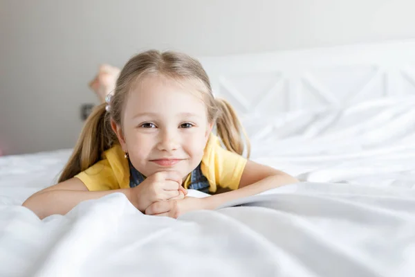 可爱的小女孩在床上笑着 — 图库照片