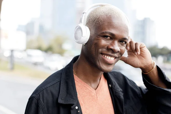 Человек с черной кожей слушает музыку в наушниках на открытом воздухе — стоковое фото