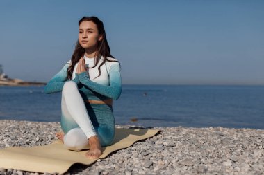 Beyaz kadın deniz kıyısında yoga yapıyor. Yüksek kalite fotoğraf