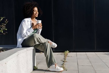 pretty young afro woman with coffee outdoors. High-quality photo