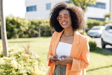 smiling Afro American woman with phone outdoors. High quality photo