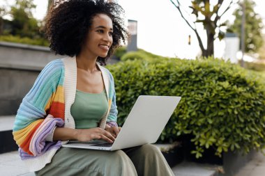 Siyah tenli kadın dışarıda dizüstü bilgisayar kullanıyor. Yüksek kaliteli fotoğraf.