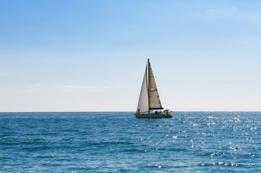 mavi ve sakin denizde küçük yelkenli tekne