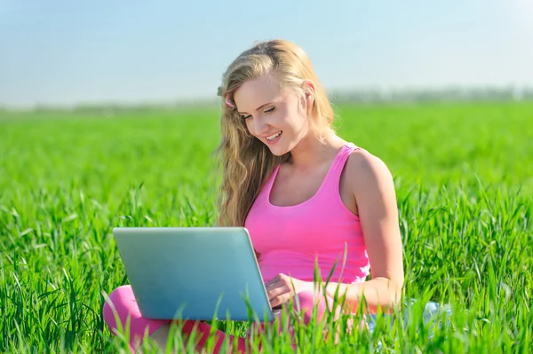 緑の草の上に座っているラップトップを持つ若い女性 — ストック写真