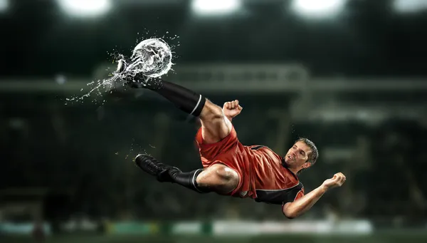 Футболист бьет по мячу на стадионе — стоковое фото