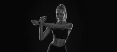 Siyah arka plandaki güçlü atletik formalı kadın spor kıyafetlerini giyiyor. Spor ve spor motivasyonu.