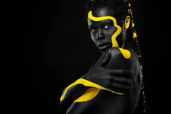 Pintura de cuerpo amarillo y negro. Mujer con arte facial. Chica joven con colorido bodypaint. Un increíble modelo afro-americano con maquillaje. —  Fotos de Stock