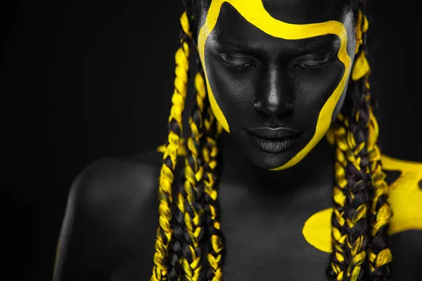 Tinta de corpo amarelo e preto. Mulher com arte facial. Rapariga com tinta corporal colorida. Um modelo afro-americano incrível com maquiagem. — Fotografia de Stock