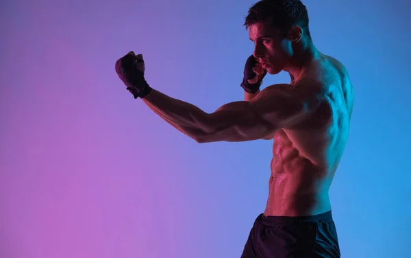 Concepto de boxeo. Deportista muay thai boxeador luchando con guantes. Aislado sobre fondo de neón. Copiar espacio. — Foto de Stock