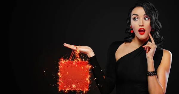 Black Friday sale concept for shop. Шоппинг девушка держит красный мешок изолированы на темном фоне. Женщина указывает на вид слева на копировальном пространстве . — стоковое фото