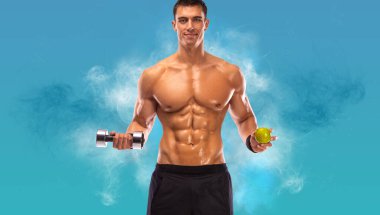Fitness ve sağlıklı gıda konsepti. Kaslı vücut geliştirici atletik adam mavi arka planda dambıl ve elmayla kaslarını şişiriyor..