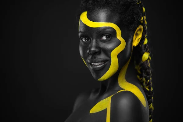 Pintura de cuerpo amarillo y negro. Mujer con arte facial. Chica joven con colorido bodypaint. Un increíble modelo afro-americano con maquillaje. —  Fotos de Stock