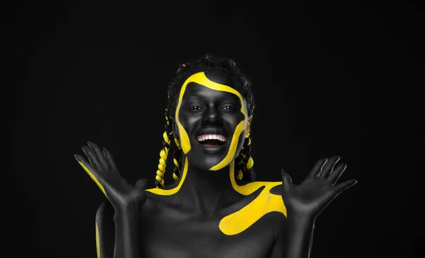Kobieta na plakacie ze złotą twarzą. Żółte i czarne kolory farby do ciała. Młoda dziewczyna z farbą do ciała. Niesamowity afro amerykański model z makijażem. — Zdjęcie stockowe