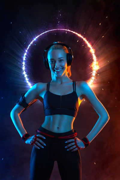 Forte donna in forma atletica su nero con luci al neon sfondo indossa in abbigliamento sportivo. Fitness e motivazione sportiva. — Foto Stock