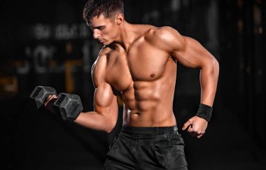 Vücut geliştirme konsepti. Güçlü kaslı vücut geliştirici atletik adam siyah arka planda halterle kaslarını şişiriyor. Vücut geliştirme konsepti. Spor beslenme reklamları için alanı kopyala.
