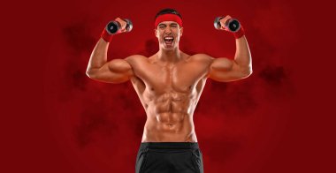 Kırmızı arka planda dambılı mutlu bir sporcu. Spor salonu tüm vücut egzersizi. Spor salonundaki kaslı erkek sporcu antrenman yapıyor. Spor eğitmeni antrenman yapıyor. Fitness motivasyonu.