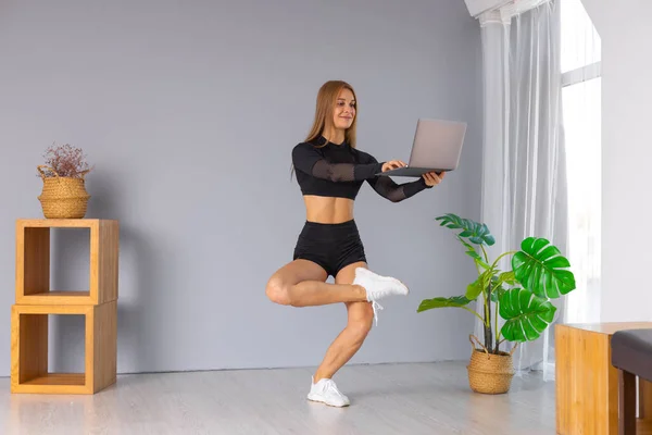 Online trainer. On-line sporten. fitness en een gezonde levensstijl concept. Vrouw met laptop doen plank oefening thuis tijdens een pandemie. — Stockfoto