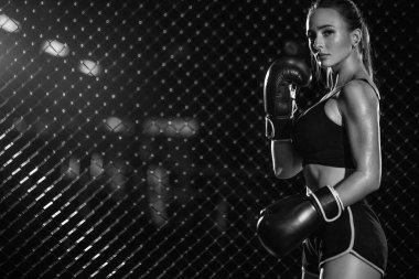 Boks ve spor konsepti. Kız sporcu Muay Thai boksörü spor salonunda eldivenli dövüşüyor..