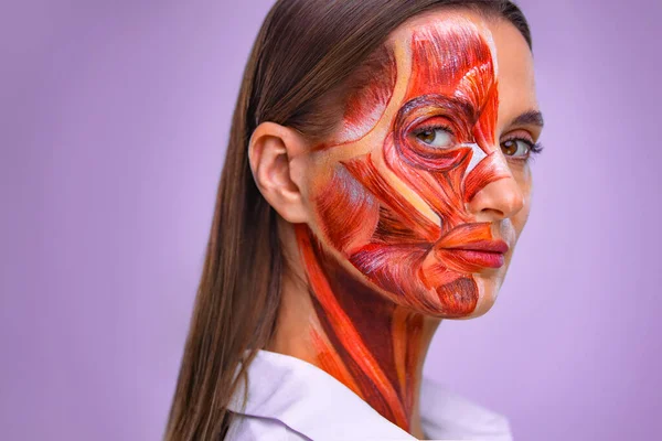 Koncepcja kosmetyczna. Młoda kobieta z połową twarzy ze strukturą mięśni pod skórą. Model do szkolenia medycznego na lekkim tle. Zamknij zdjęcie ludzkiej anantomii twarzy. — Zdjęcie stockowe