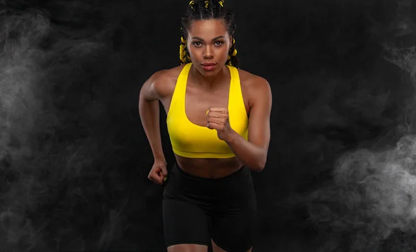 Futás! Erős, fekete hátterű, sportruhában rohangáló nő. Fitness és sport motiváció. Futó koncepció. — Stock Fotó