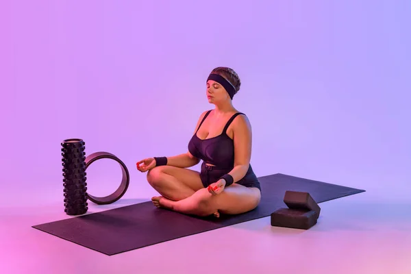 Retrato de gordura jovem praticando ioga interior. Tamanho bonito mais modelo prática asana na classe. Calma e relaxe no fundo rosa. — Fotografia de Stock