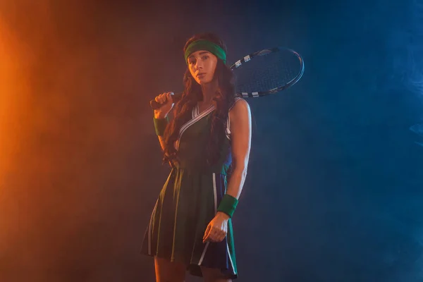 Tenisista z rakietą w odzieży sportowej. Kobieta sportowiec gra ciemne tło. — Zdjęcie stockowe