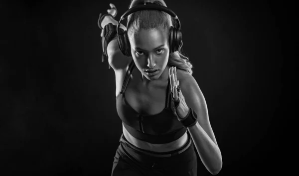 Löpare koncept. Sprutkörning. Stark atletisk kvinna kör på svart bakgrund bär i sportkläder. Fitness och idrottsmotivation. — Stockfoto
