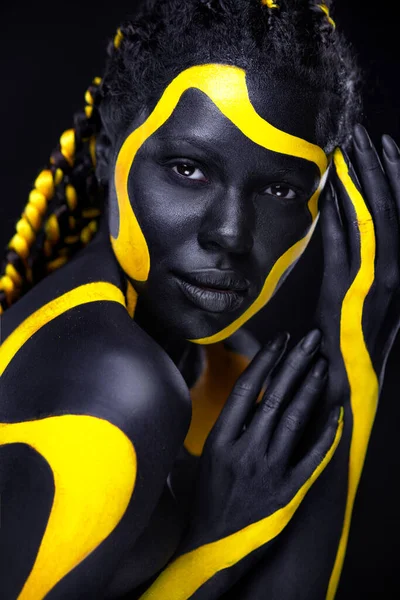 Żółta i czarna farba. Kobieta ze sztuką twarzy. Młoda dziewczyna z farbą do ciała. Niesamowity model z makijażem. — Zdjęcie stockowe