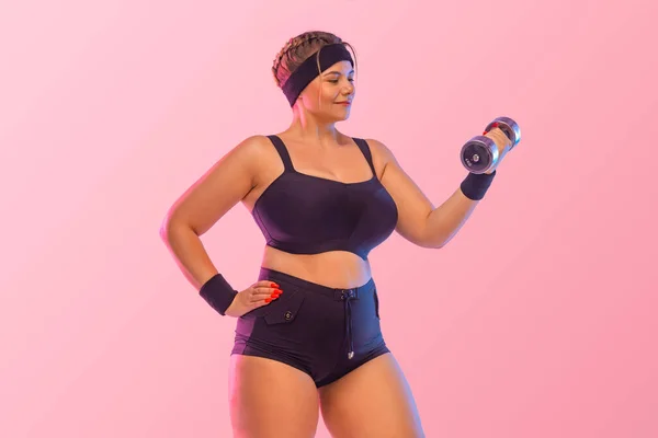 Mujer gorda joven deportista. Aptitud corporal positiva. La chica quiere perder peso con pesas. Foto para diseño publicitario de productos de pérdida de peso y equipos de fitness. —  Fotos de Stock