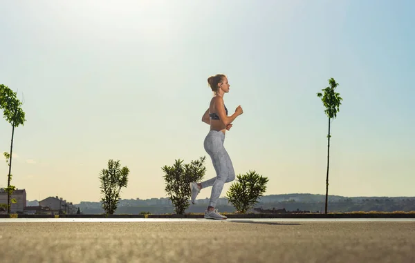 Jogging run. Strong athletic woman running on black background wearing in the sportswear. Fitness and sport motivation. Runner concept. — Foto Stock