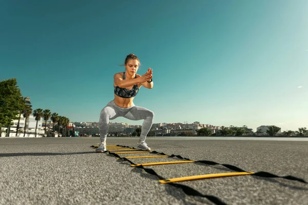 Junge Sportlerin trainiert Springen auf der Agility-Leiter — Stockfoto