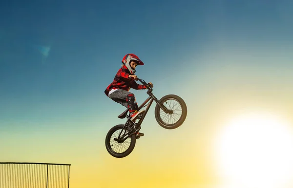 A teenager BMX Racing Rider performs tricks in a skate park on a pump track