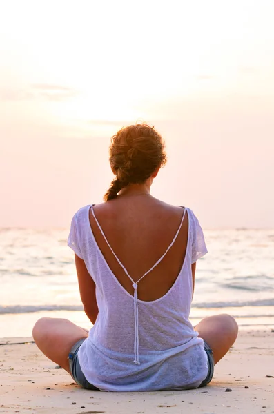 Vrouw zit op het strand bij zonsopgang — Stockfoto