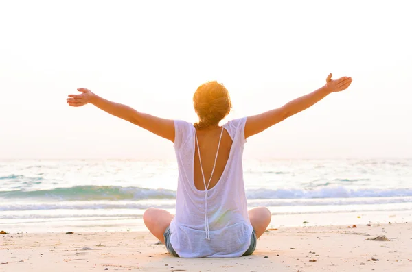 Vrouw zit op het strand bij zonsopgang — Stockfoto