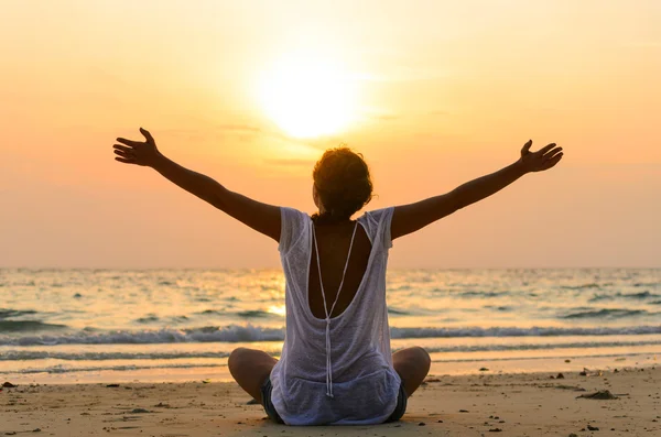 Vrouw zit op het strand bij zonsopgang — Stockfoto