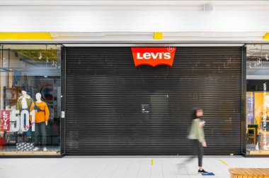 SAINT-PETERSBURG, RUSSIA - MARCH 30, 2022: Sanctions in Russia. Closed Levis store in Russian shopping mall due to armed conflict in Ukraine. Customers walking by the locked doors.