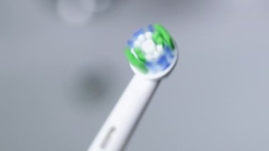 Electric toothbrush with new rotating head. View of ultrasonic tooth brush with replaced head in bathroom. White toothbrush for oral hygiene and cavity prevention. Slow motion 240fps