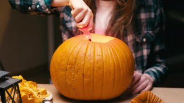 Illuminating pumpkin for Halloween. Woman sitting, lighting and showing out candle lit halloween Jack O Lantern pumpkin at home for her family.