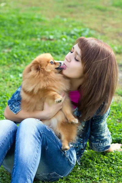 Pomeranian γλείφει μια νεαρή γυναίκα στο πρόσωπο — Φωτογραφία Αρχείου