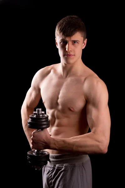 Молодой мускулистый человек тренируется с гантелями — стоковое фото