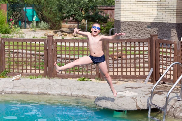 Pojken hoppar i poolen — Stockfoto