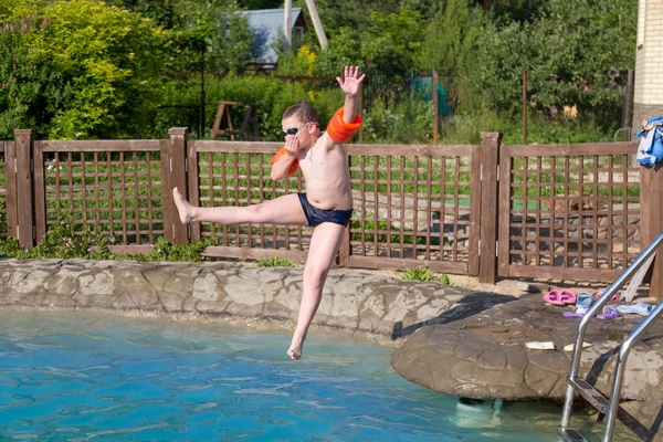 Pojken hoppar i poolen — Stockfoto