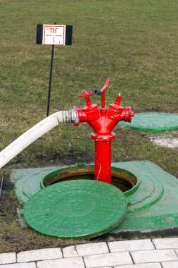 Red fire hydrant stands in manhole clipart