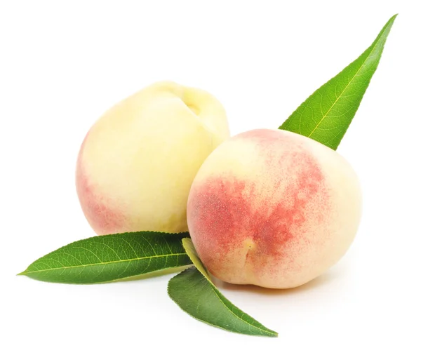 Rijpe perzik vruchten met groene bladeren — Stockfoto