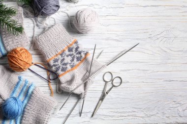 Beyaz ahşap arka planda düz örgü ve kış aksesuarları.
