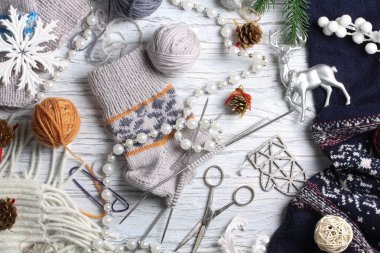 Beyaz ahşap arka planda düz örgü ve kış aksesuarları.